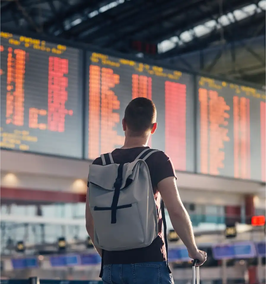 Hombre mirando panel de salidas y viendo la cancelación de su vuelo