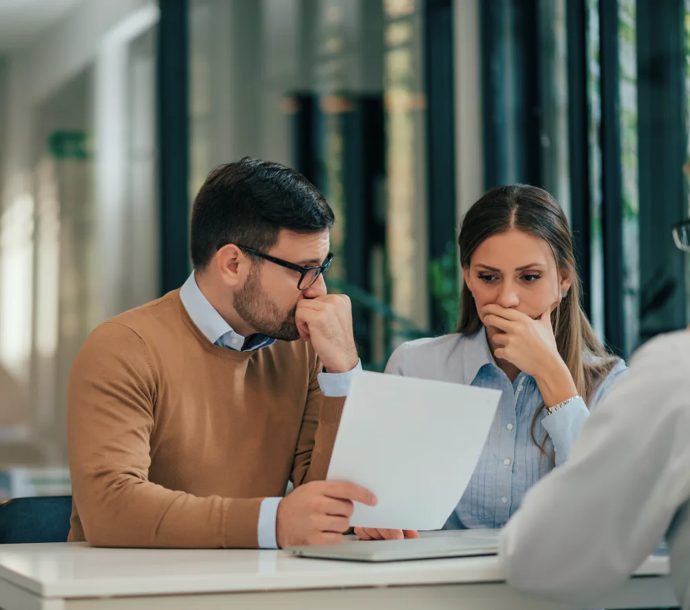 Pareja con problemas financieros mirando documentos en la oficina del banco